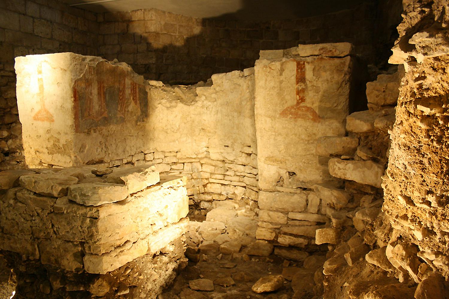 古老的石头遗迹，部分墙壁，地面上有瓦砾，一面墙上有淡淡的红色标记。