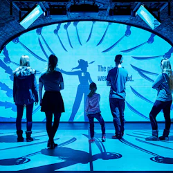 Fem personer, sedda bakifrån, står framför en stor skärm och visar en skugga av en figur och utsträckta svärd.