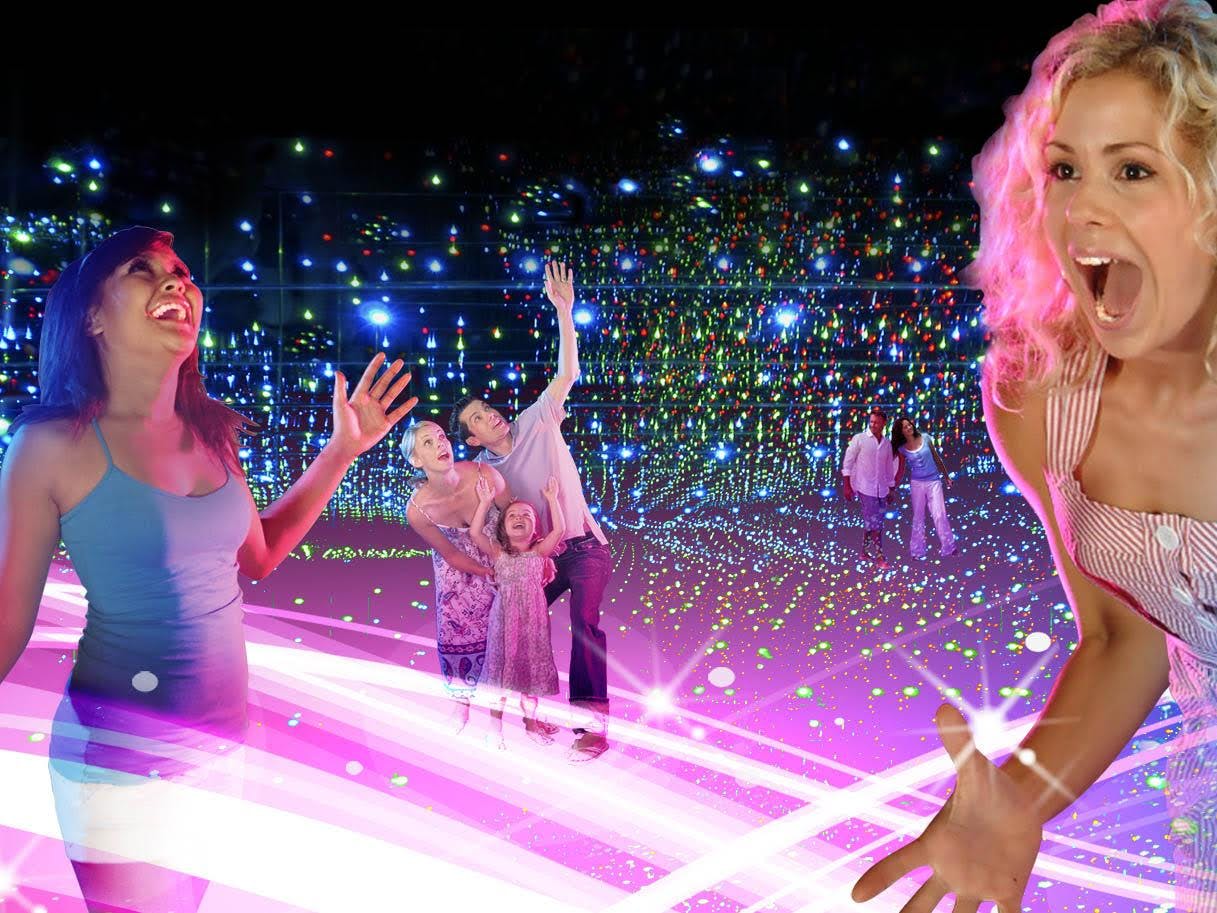 People are excited and amazed in a dazzling space filled with multicolored lights and reflective surfaces.