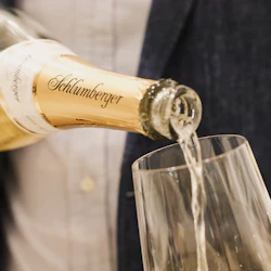 En person häller upp mousserande vin från en flaska i ett glas.