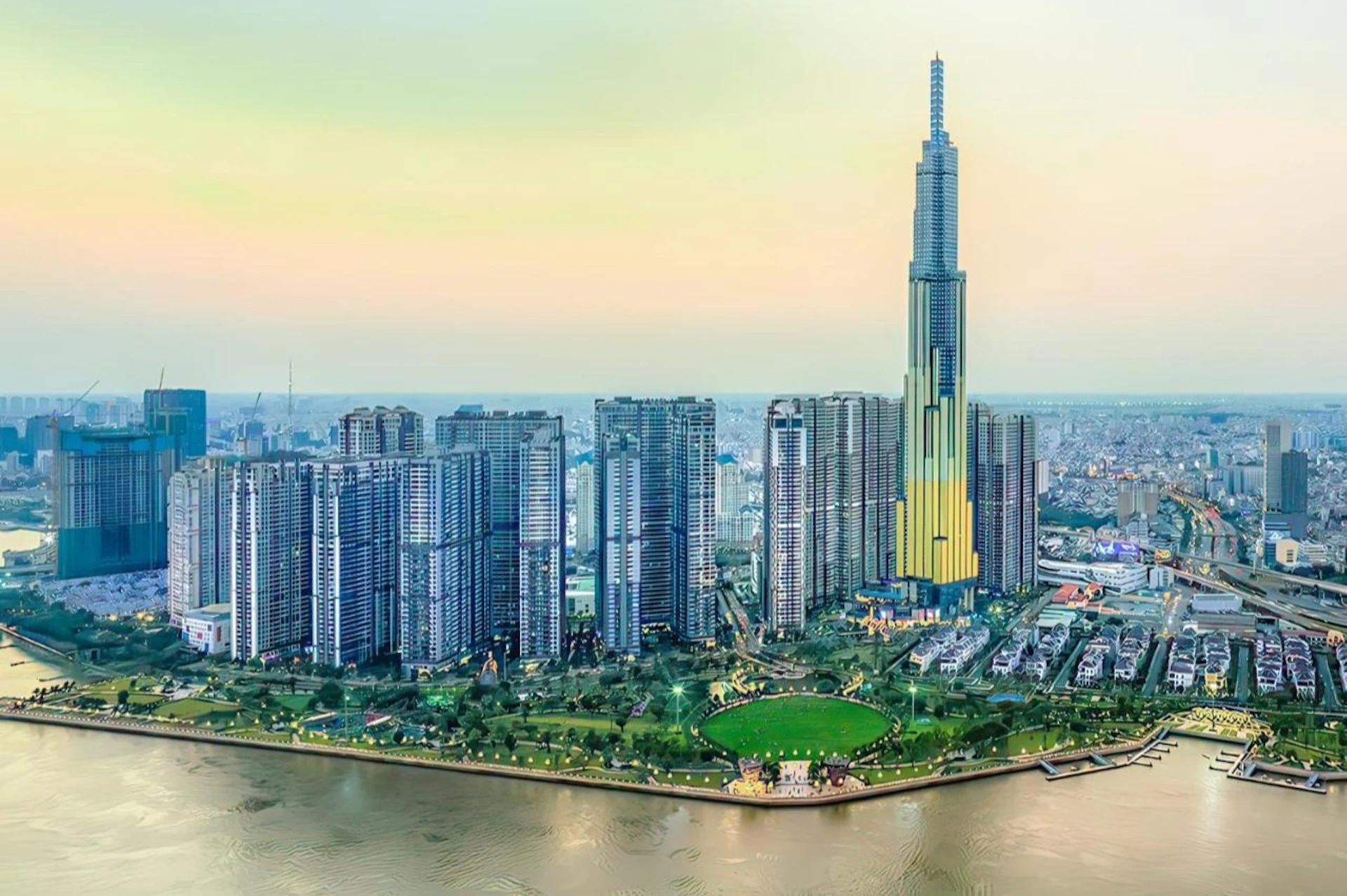 Cityscape with a river in the foreground, featuring a cluster of modern skyscrapers, including a prominent, tall building in the center.