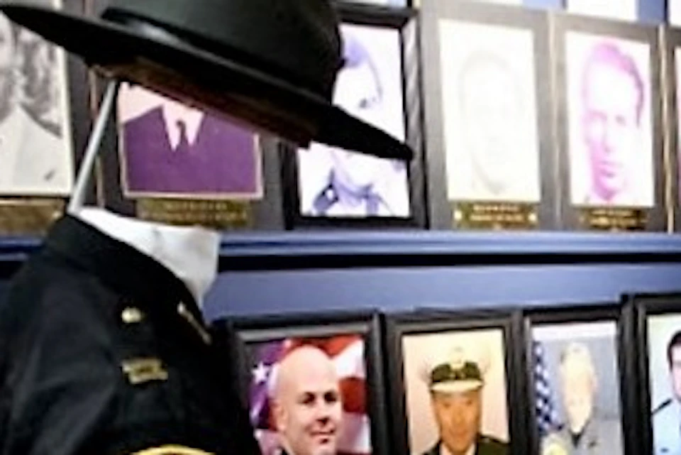 A museum display featuring framed photos of military personnel, a mannequin dressed in a uniform, and a glass case with artifacts.
