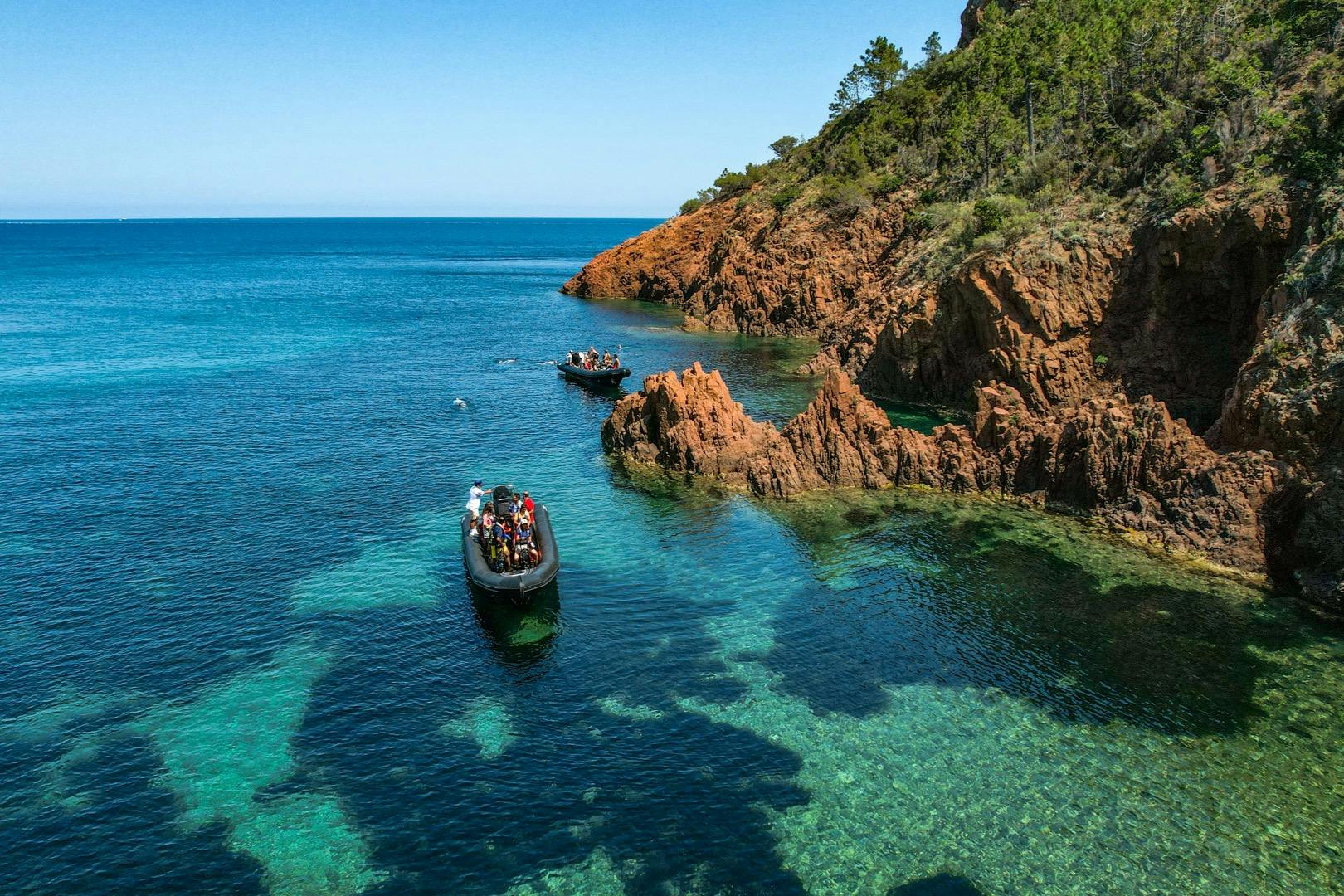 승객이 탑승한 두 척의 팽창식 보트는 바위가 많고 숲이 우거진 해안선 근처에서 맑고 푸른 바다를 항해합니다.