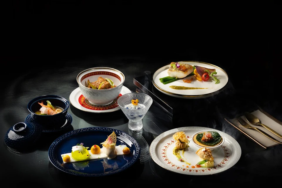 An arrangement of gourmet dishes on elegant plates and glassware, featuring colorful and intricate food presentations.