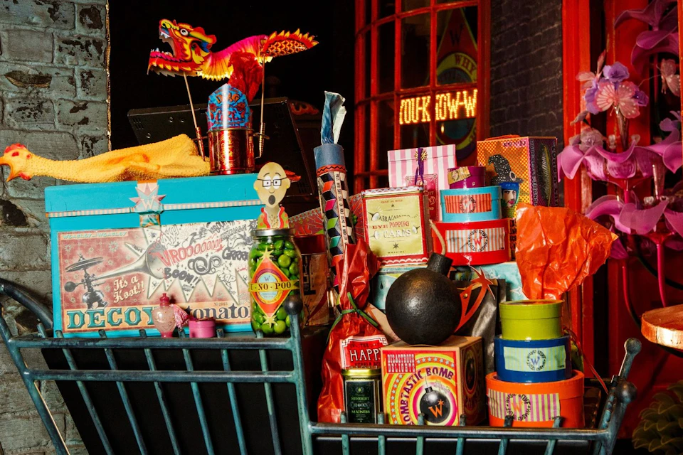 A colorful collection of whimsical items in a display, including boxes, a toy dragon, and various vintage-style packaging.