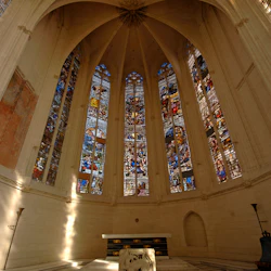 Katedralinteriör med högt, välvt tak, stora glasmålningar och ett utsmyckat altare på mönstrat marmorgolv.