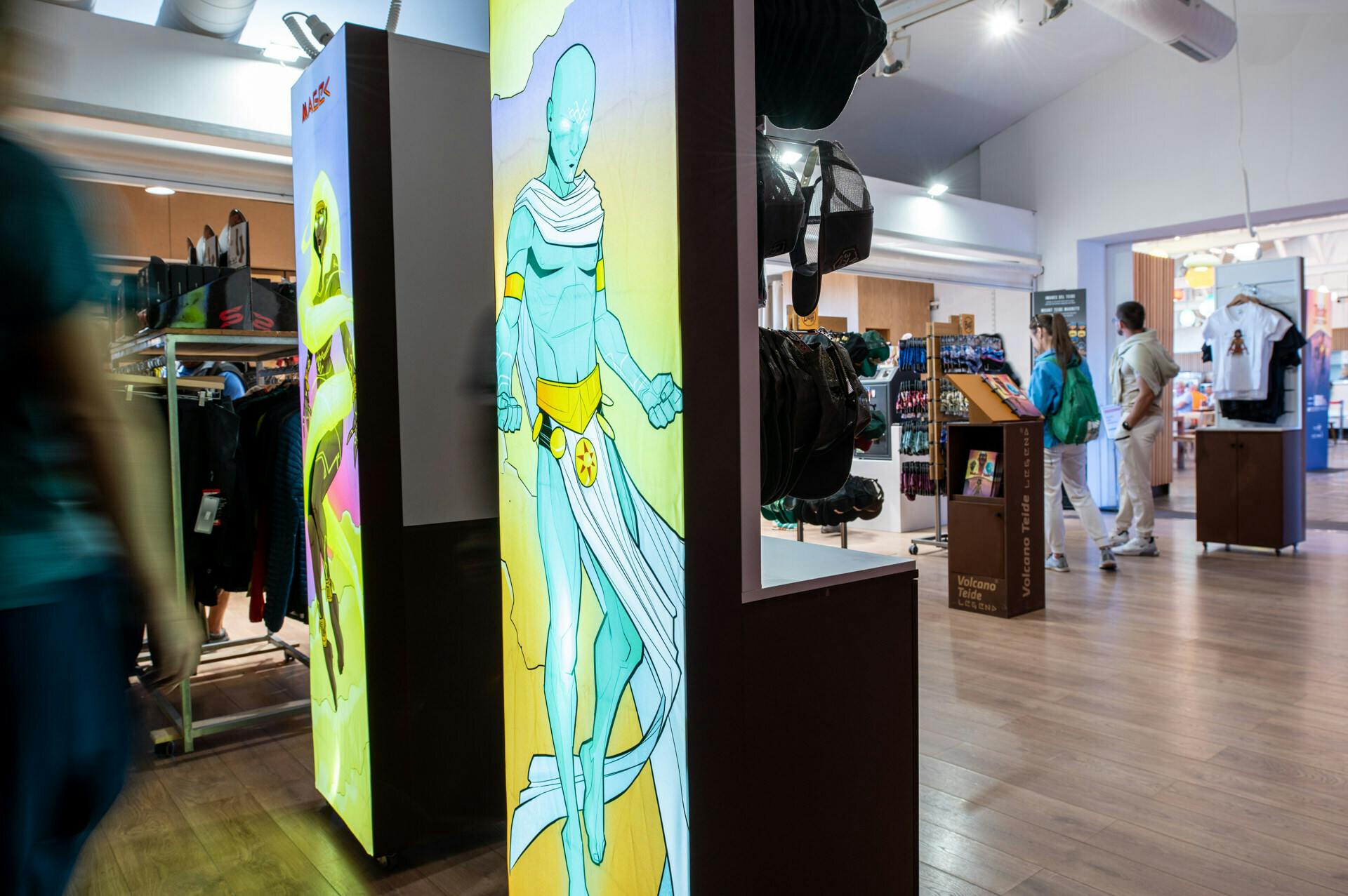 En butik, der viser en stor plakat af en blå muskuløs karakter med en hvid kappe. Nogle kunder er synlige i baggrunden.