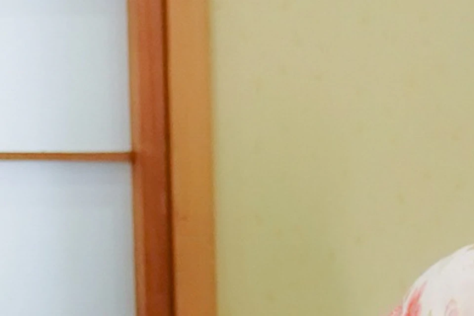 Two women in traditional Japanese kimonos sitting on tatami mats in a room with shoji screens, smiling at each other.