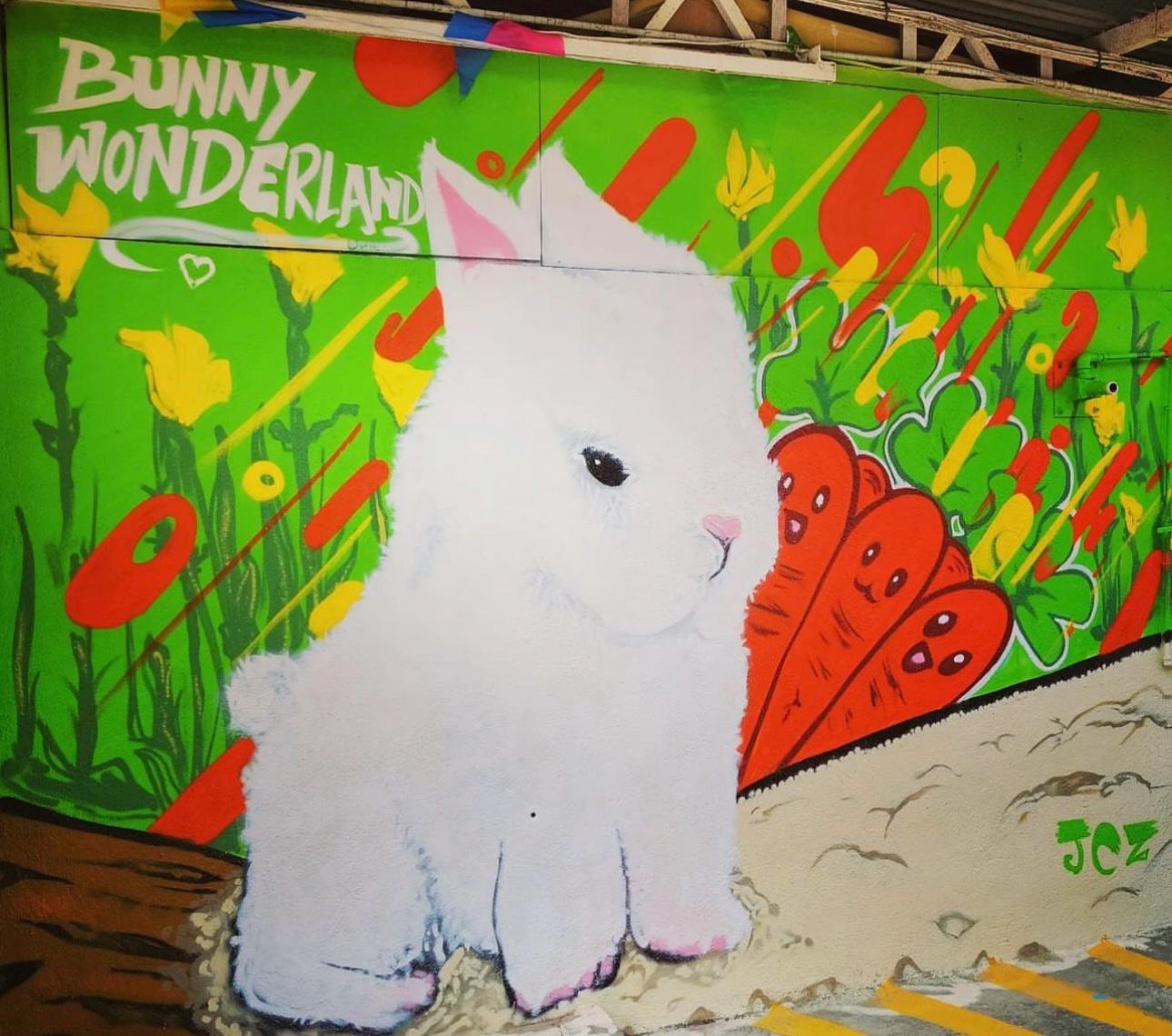 A colorful mural featuring a white bunny, vibrant carrots, yellow flowers, and the text "Bunny Wonderland" on a green background.
