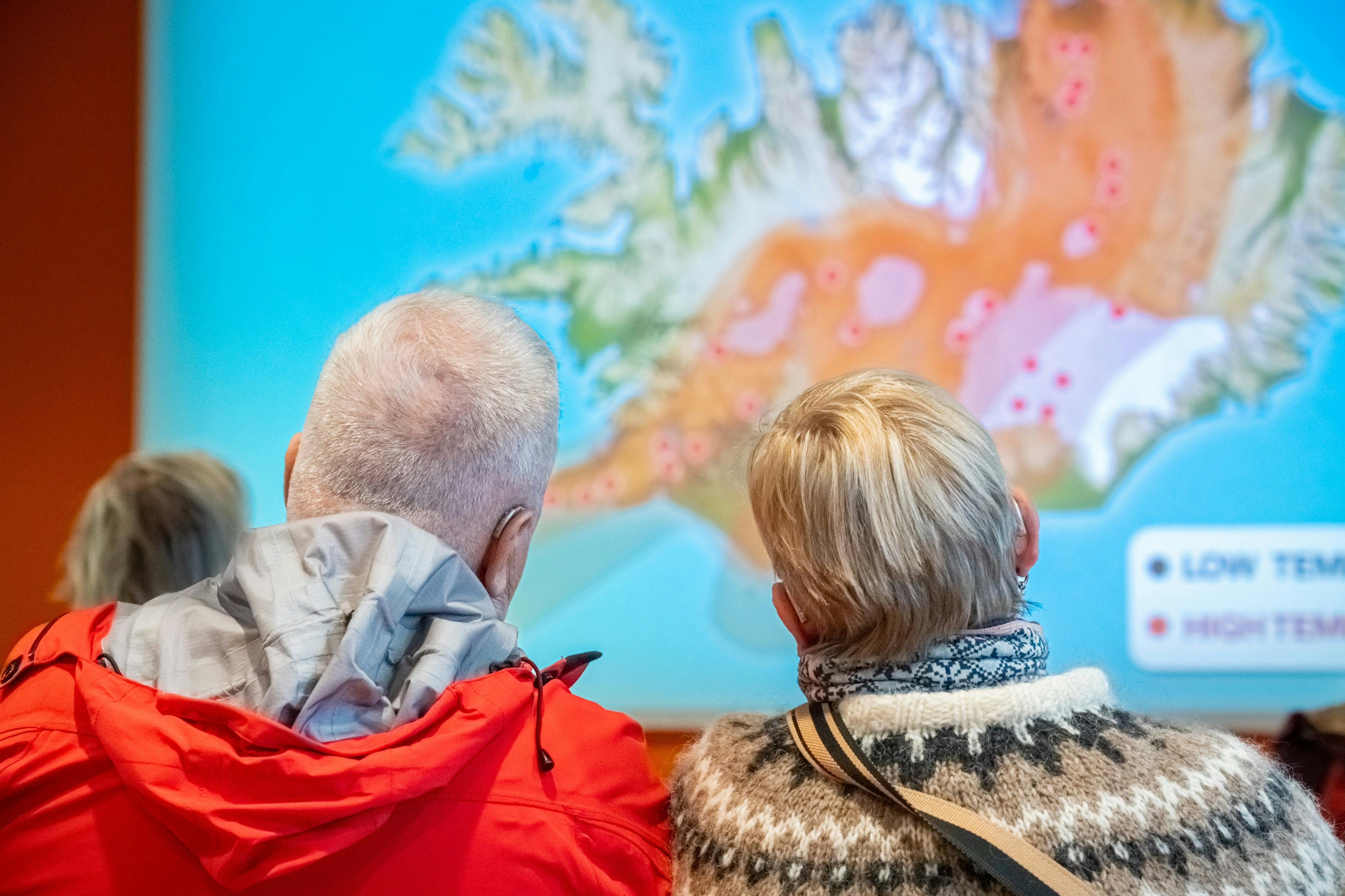 Zwei Personen in warmer Kleidung stehen vor einer Karte mit Temperaturdaten, auf der niedrige und hohe Temperaturzonen in rot und blau markiert sind.