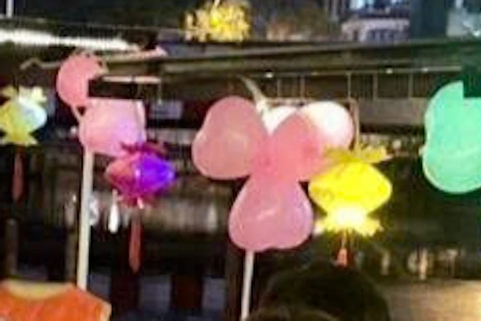 People wearing orange life jackets sitting around a table with drinks, listening to a man speak. Balloons and lights decorate the area.