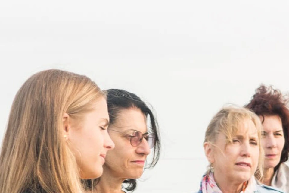 A group of people outdoors, with one person holding a picture and showing it to others.