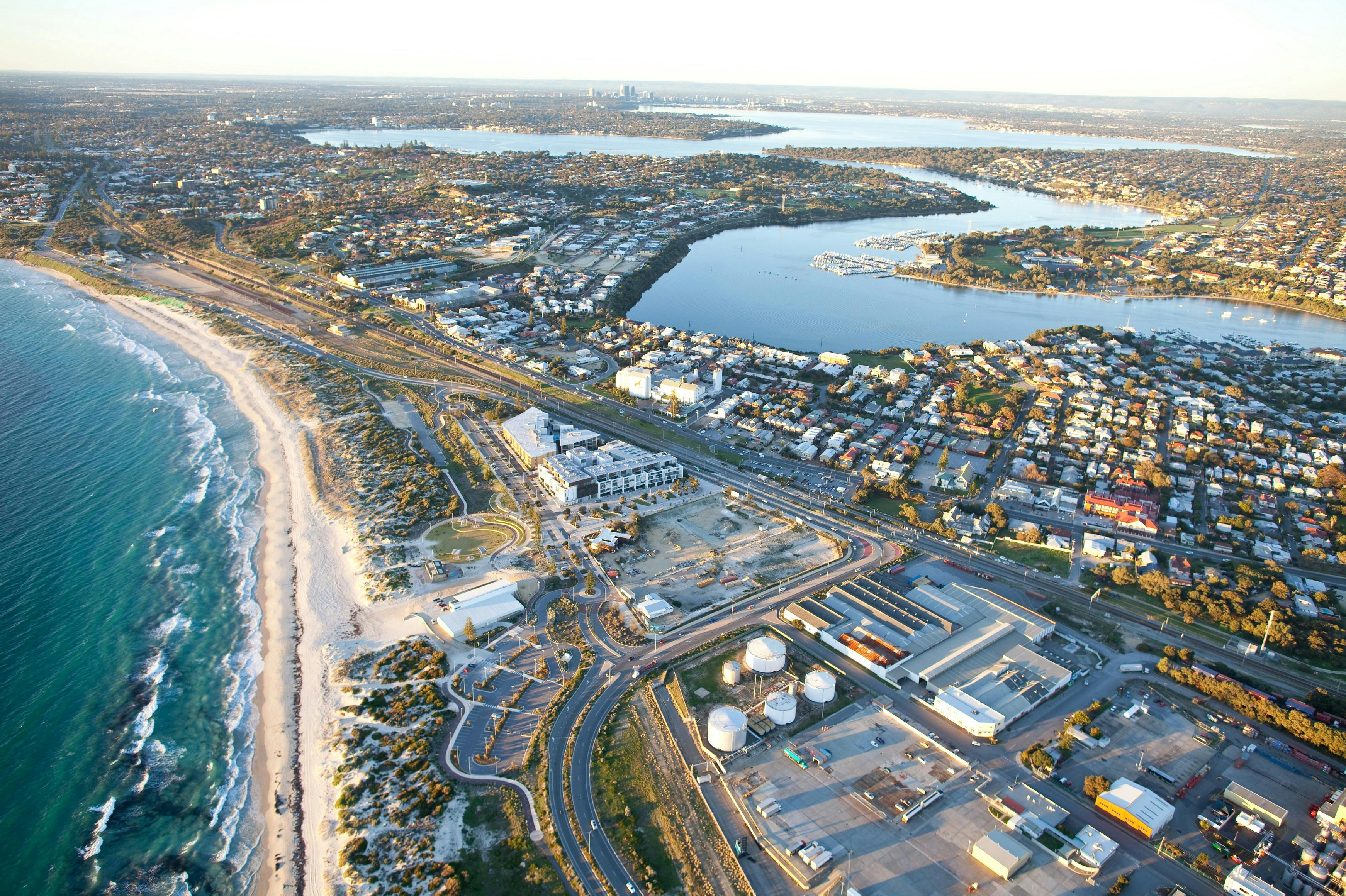 Luchtfoto van een kuststad met woonwijken, industriële gebouwen, een strand en een rivier of riviermonding.