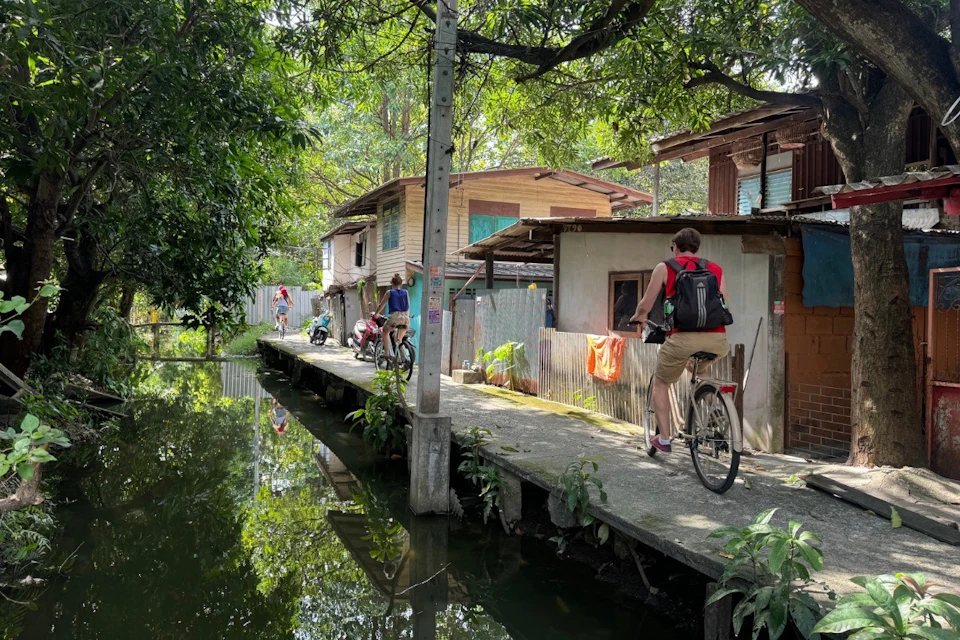 Cyclists riding along a peaceful canal path in Bangkok’s local neighborhood