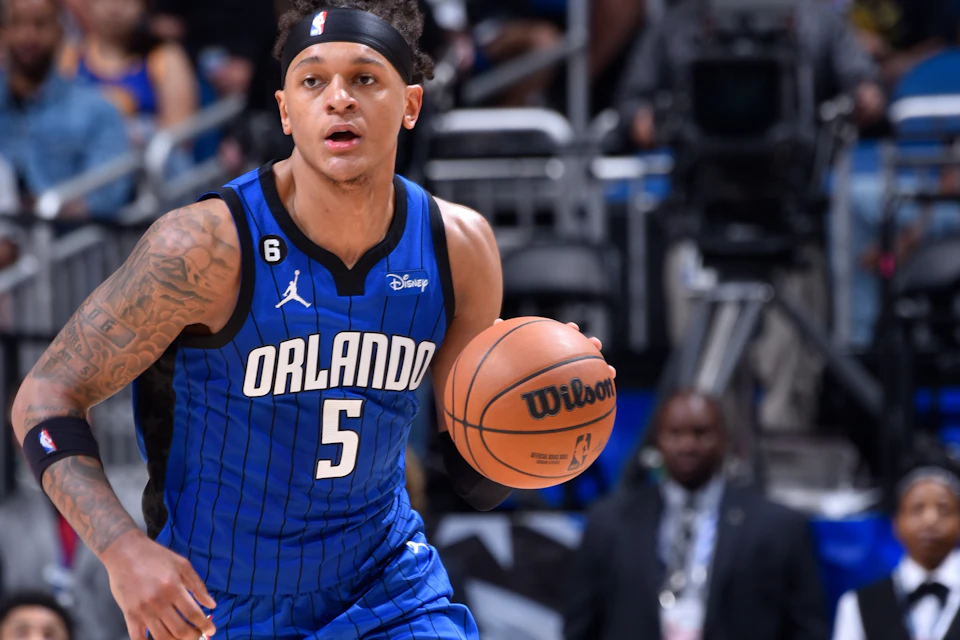 Basketball player in a blue Orlando jersey holding a basketball, mid-action on the court.