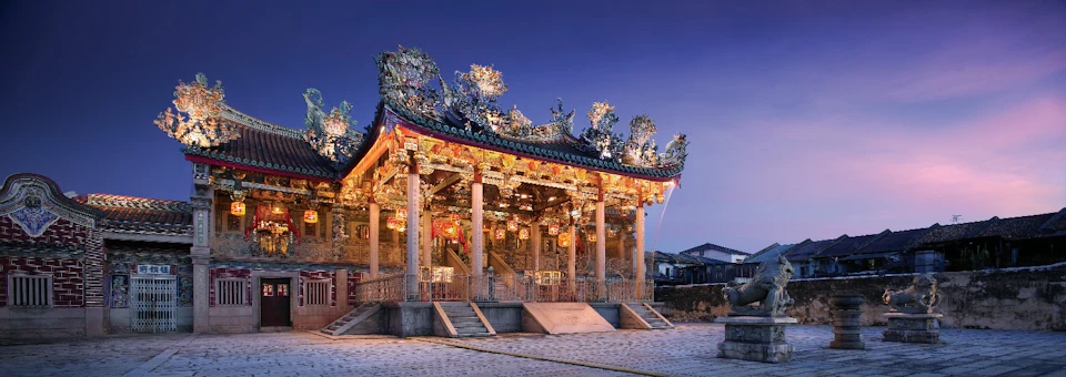 A traditional Chinese-style building with ornate decorations and warm lighting, set against a twilight sky.