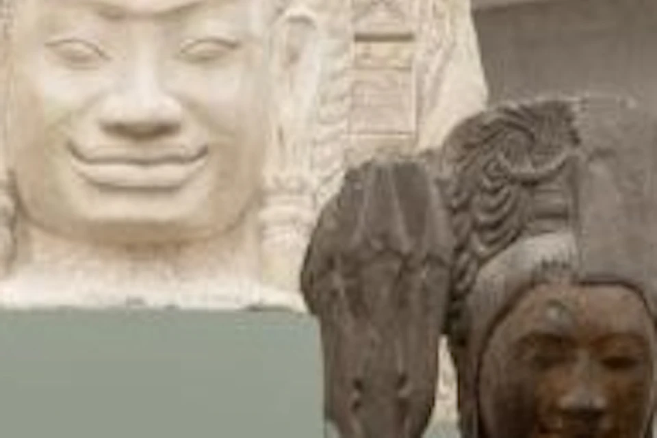 A museum exhibit featuring ancient sculptures, including a large head sculpture and several smaller statues on pedestals.
