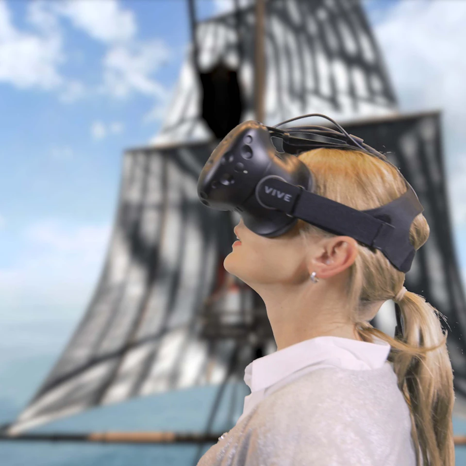 A person wearing a VR headset with a sailing ship in the background.