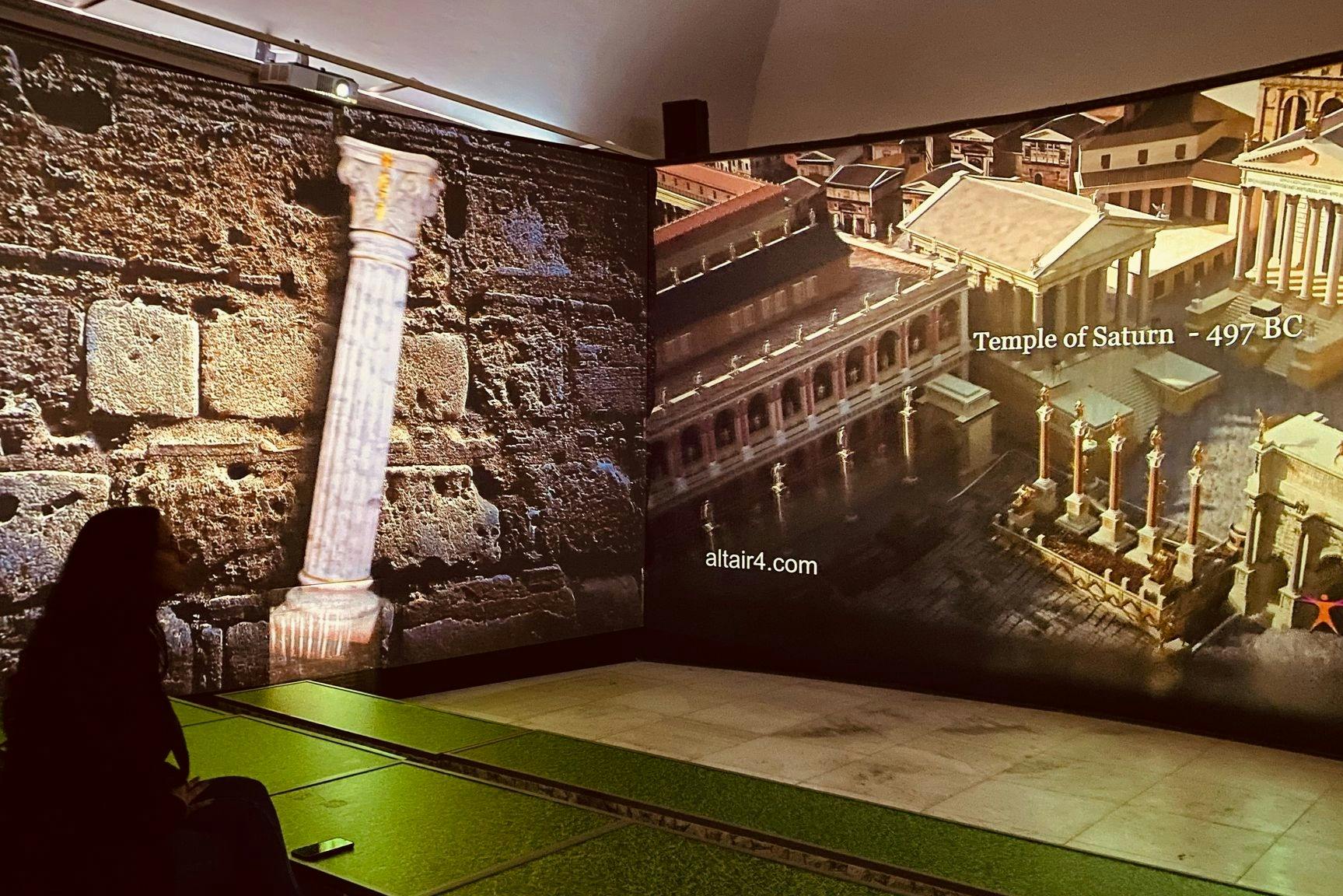 Un'esposizione museale con una colonna e un rendering digitale del Tempio di Saturno nell'antica Roma. Il testo recita 