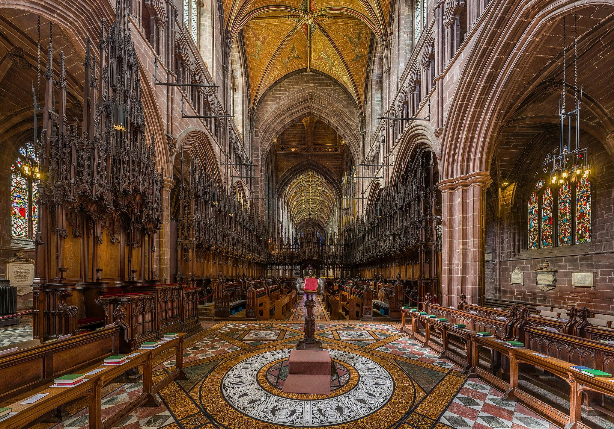 Ornate cathedral interior with intricate wooden carvings, arched ceilings, stained-glass windows, and decorative tiled flooring.