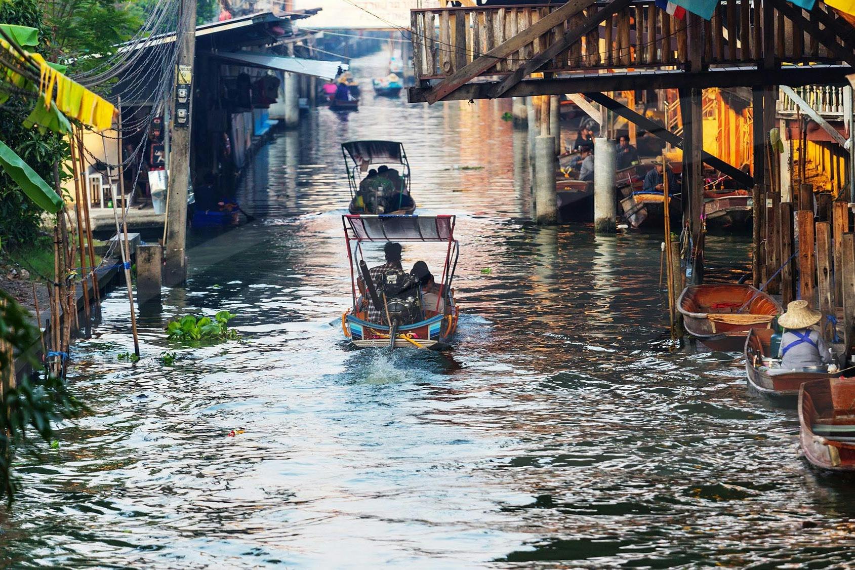 The long tail boat heading in direction of the floating market