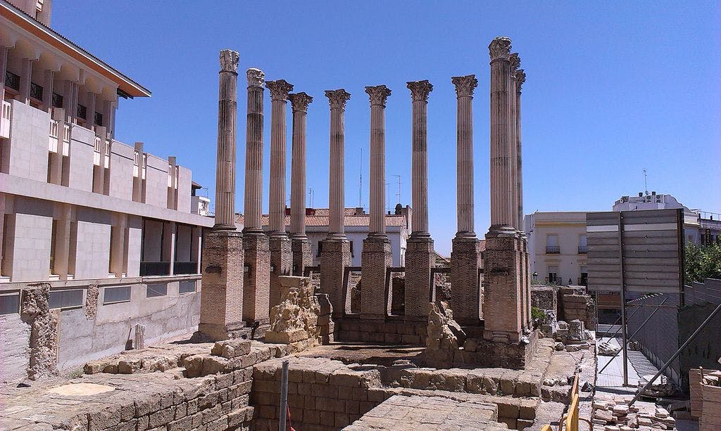 八根高大的古罗马柱子，装饰华丽的首都，部分修复，晴朗的蓝天，坐落在现代建筑之间。