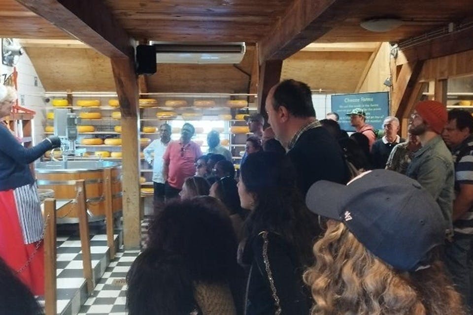 Un groupe de personnes réunies à l'intérieur d'une structure en bois, certaines assises, d'autres debout, regardant attentivement dans la même direction.