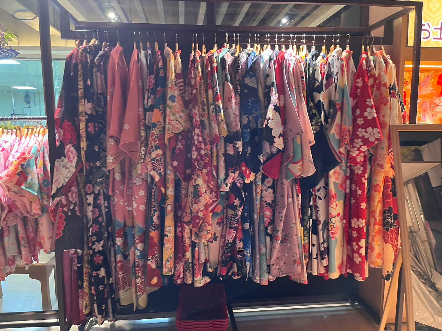 A rack displaying numerous colorful kimonos with floral patterns hanging neatly in a store.