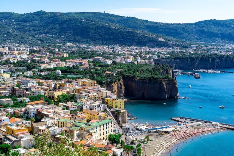 这座海滨小镇拥有五彩缤纷的建筑、沙滩、悬崖和深蓝色的大海，所有这些都坐落在绿色的山丘上。