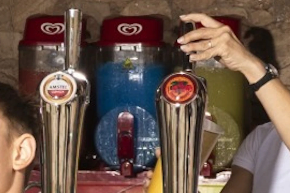 A group of people in swimwear standing at a counter labeled 'Treasure Tavern,' with drinks and snacks visible behind.