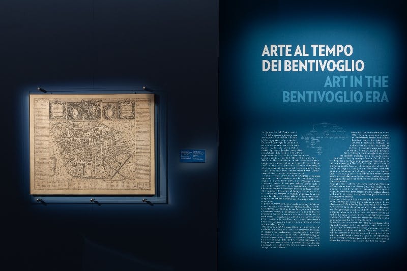 Una galleria museale con pavimenti in legno, opere d'arte a parete, un soffitto dettagliato e sculture contemporanee in esposizione.