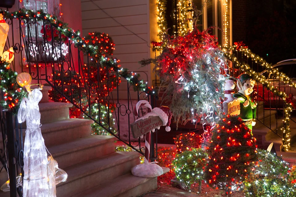 A staircase decorated with red and white Christmas lights, greenery, and holiday signs, creating a festive atmosphere.