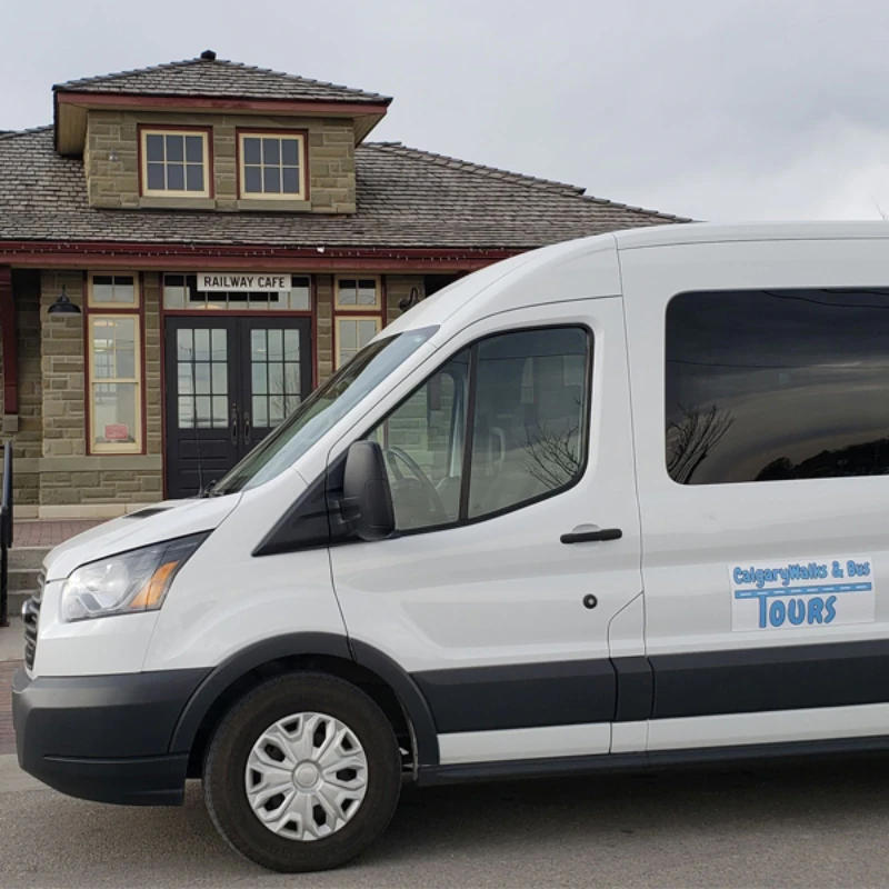 White tour van parked in front of a historic building labeled "Railway Cafe."