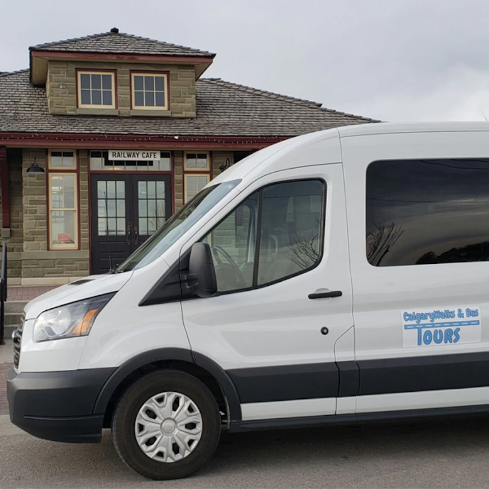 White tour van parked in front of a historic building labeled "Railway Cafe."