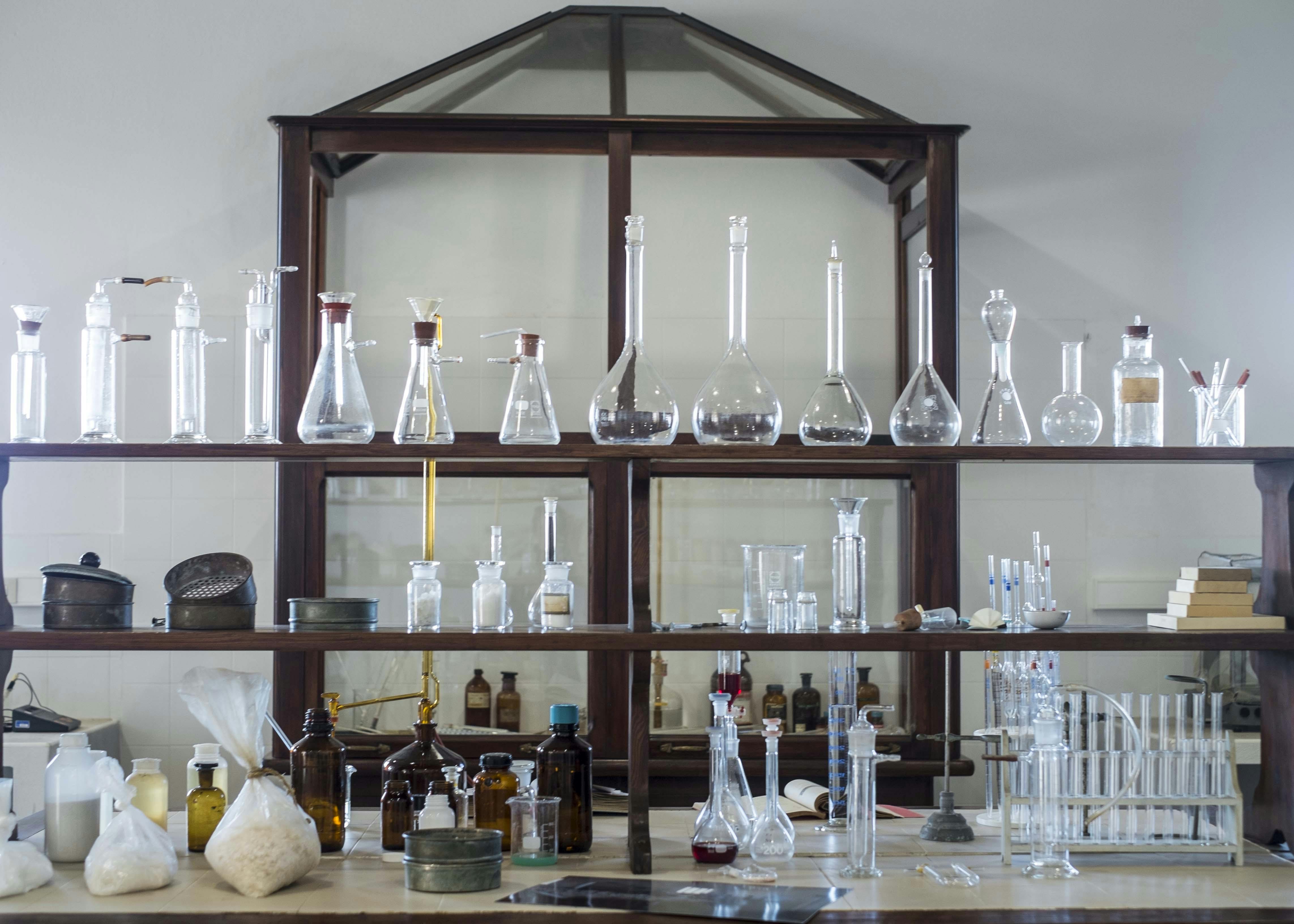 Une étagère de laboratoire remplie de béchers, de flacons, de bouteilles et d'autres équipements scientifiques en verre.