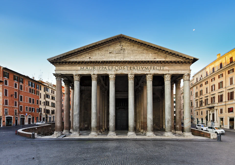Ancient Roman building with a grand facade featuring tall columns and a triangular pediment, located in a city square.