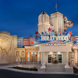 Entrance of Hollywood Wax Museum with a colorful sign, surrounded by replicas of city buildings and a large King Kong figure.