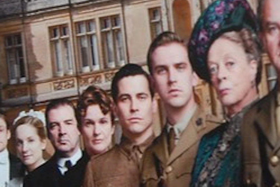Promotional poster for Downton Abbey Series Two featuring the cast in front of a grand building.