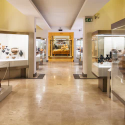 Museikorridor med glasmonter som visar antika keramik och artefakter. En gyllene sarkofag syns i slutet.