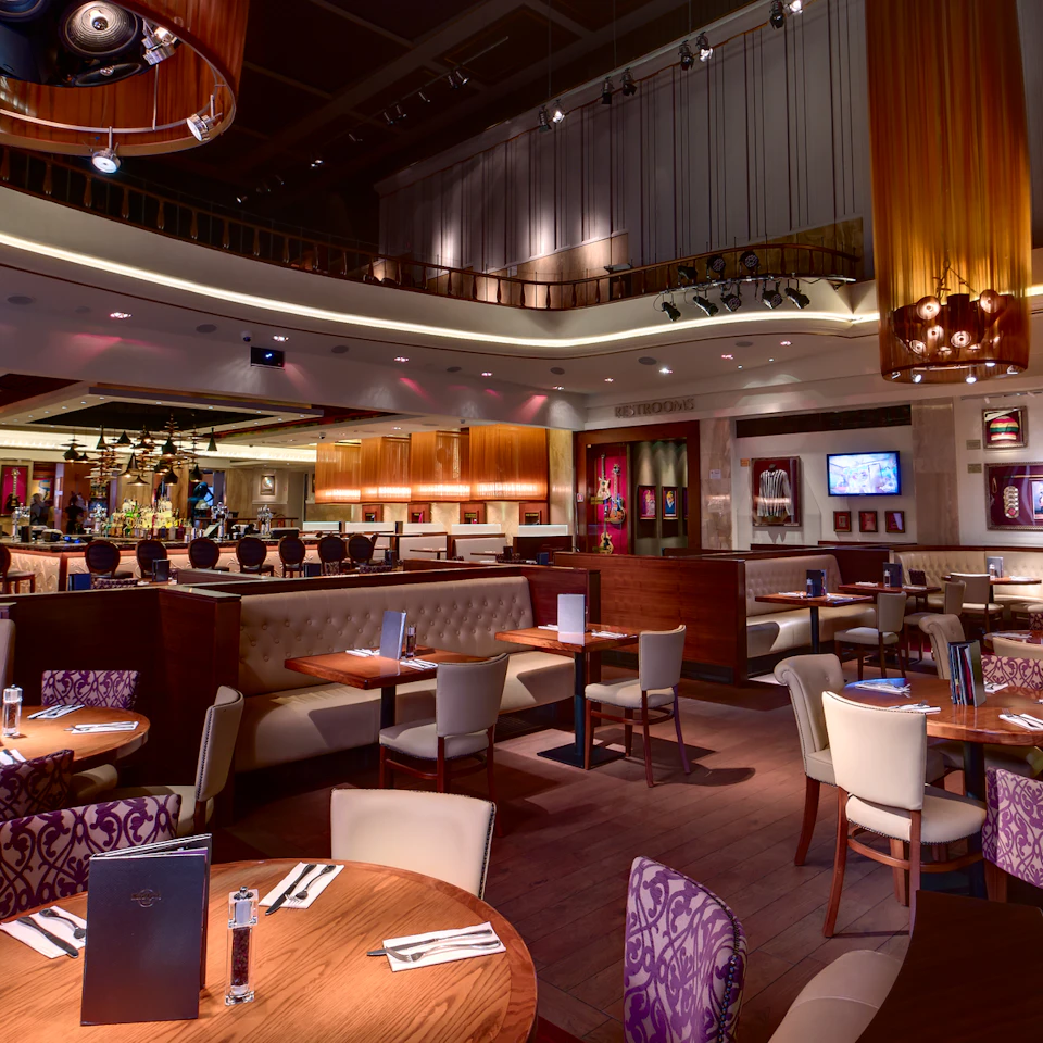 A modern restaurant interior with tables and chairs arranged neatly, dim lighting, and decorative art on the walls.