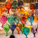 Colorful glass balloons hanging together, showcasing a variety of vibrant hues and creating a festive, decorative cluster.