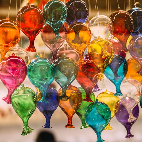 Colorful glass balloons hanging together, showcasing a variety of vibrant hues and creating a festive, decorative cluster.