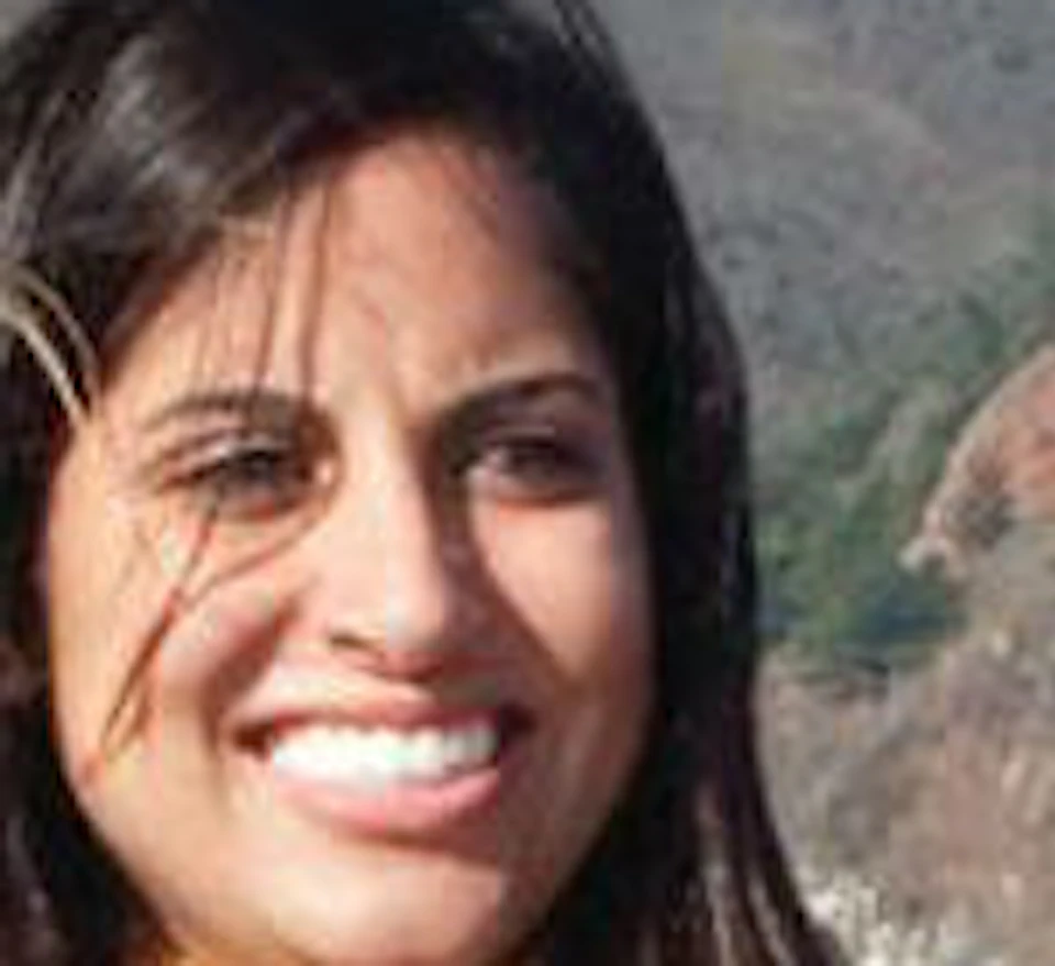 Three women smiling in front of the Golden Gate Bridge with clear blue sky and hilly landscape in the background.