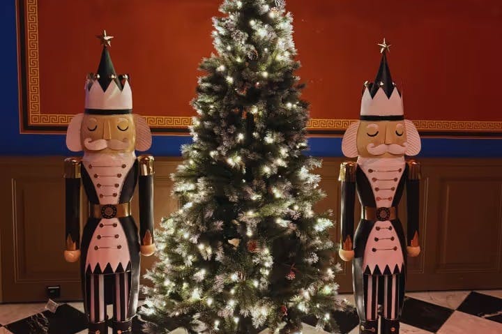 Et dekoreret juletræ flankeret af to store Nøddeknækkerfigurer inde i et rum med røde og blå vægge.