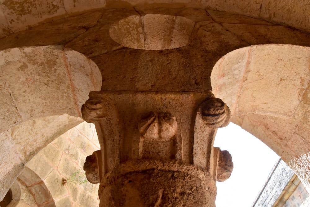 Κοντινό πλάνο αρχαίας πέτρινης στήλης με λεπτομερή γλυπτά που στηρίζουν μια αψίδα, αναδεικνύοντας τις υφές και τη δεξιοτεχνία.