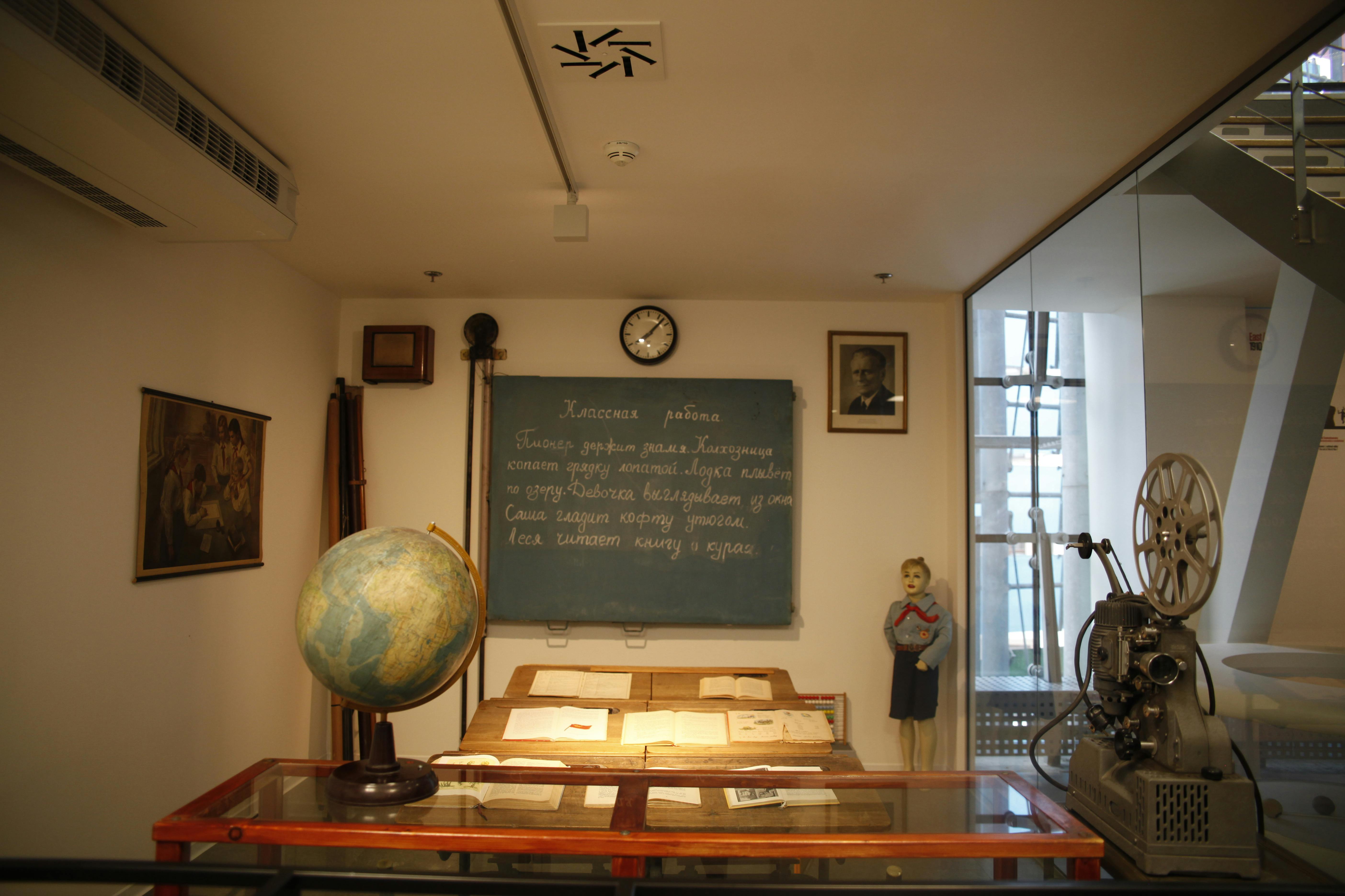 博物馆展出了一间老教室，配有黑板、玻璃书展柜、地球仪、人体模型和老式电影放映机。