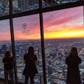 turistas contemplando el paisaje urbano de chicago en la cima del observatorio 360 Chicago