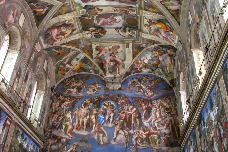 Intricately painted ceiling and wall depicting religious scenes and figures in the Sistine Chapel.
