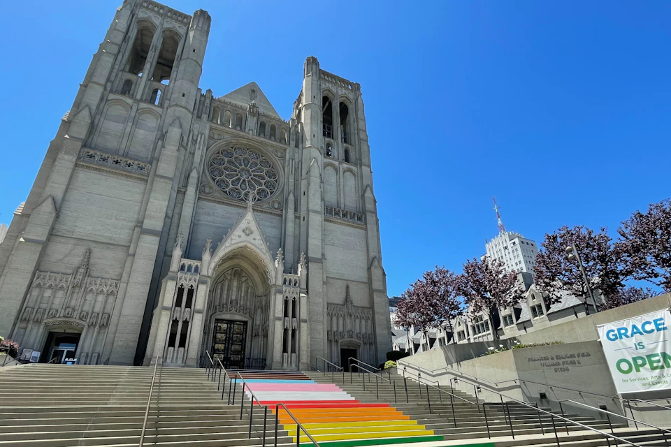 A large cathedral with gothic architecture, featuring rainbow-colored steps leading up to the entrance.