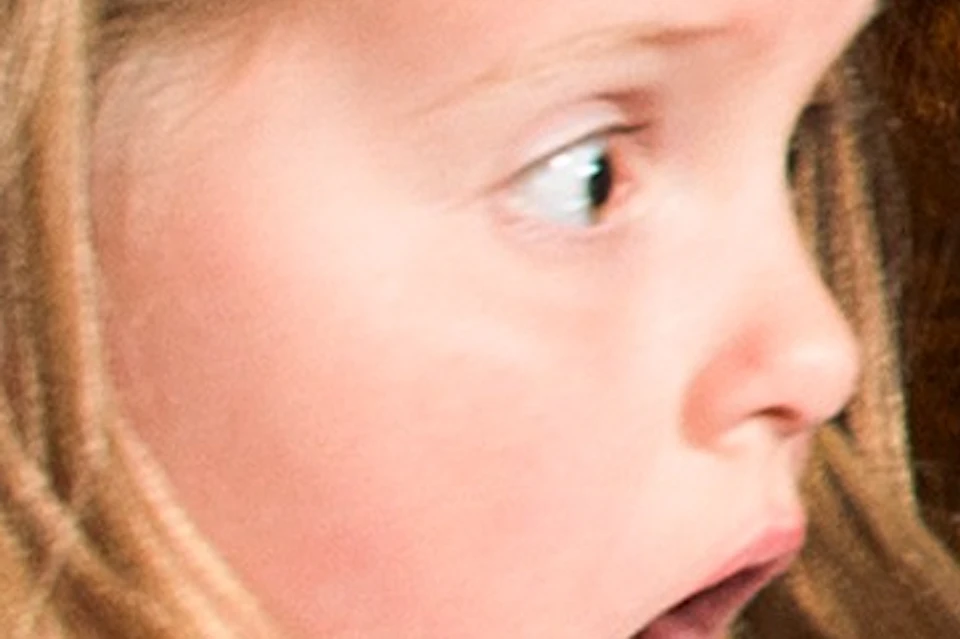 A young girl looks surprised at a snarling wolf display in a museum or exhibit setting.